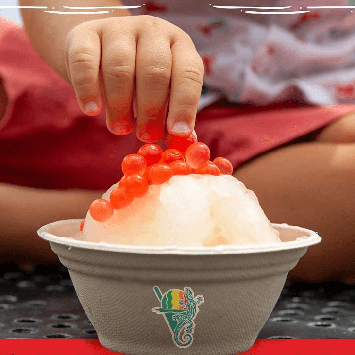 A child's hand grabs boba from the top of a bowl of shave ice, a Big Island vegan dessert